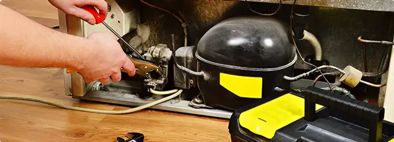 Refrigerator repair technician fixing the compressor and wiring in Pleasant Grove, AL
