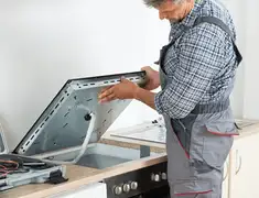 Appliance repair technician installing a built-in cooktop in Birmingham, AL