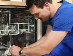 Dishwasher repair technician inspecting and servicing an open dishwasher in Birmingham, AL