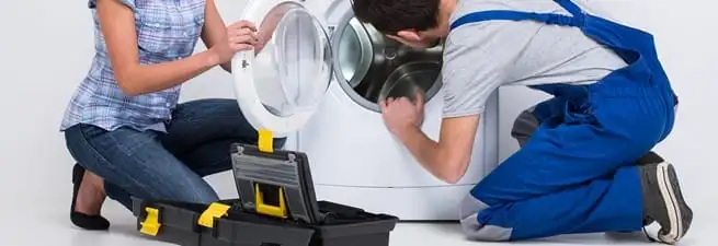 Washer repair technician inspecting a front-load washing machine with tools in Birmingham, AL