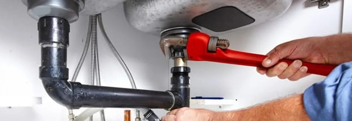 Garbage disposal repair technician tightening the sink drain and disposal connection in Birmingham, AL