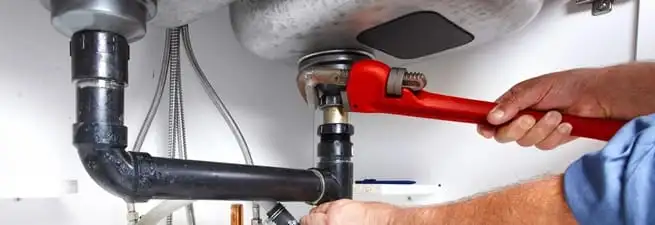 Garbage disposal repair technician tightening the sink drain and disposal connection in Birmingham, AL