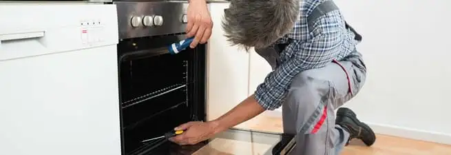 Oven repair technician inspecting and servicing an electric oven in Birmingham, AL