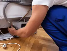 Appliance repair technician fixing refrigerator water line and connections in Birmingham, AL