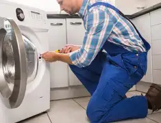 Washing machine repair technician servicing a front-load washer in Birmingham, AL