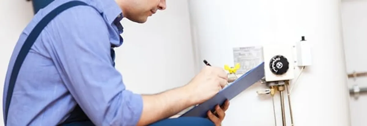 Water heater repair technician inspecting the unit and recording service notes in Birmingham, AL