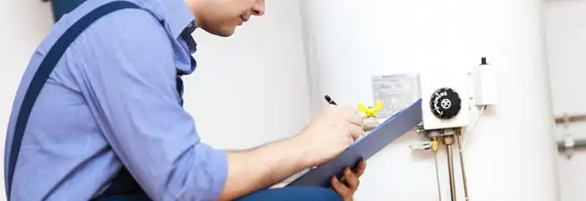 Water heater repair technician inspecting the unit and recording service notes in Birmingham, AL