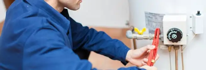 Water heater repair technician adjusting the temperature control and gas valve in Birmingham, AL